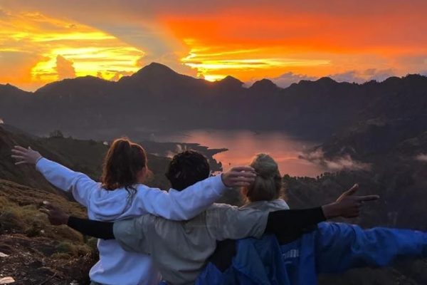 Trekkers enjoying a beautiful sunrise view during Rinjani trekking overlooking Segara Anak Lake at Mount Rinjani Lombok Indonesia
