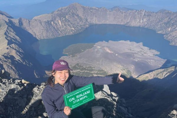 Hiker reaching the summit during Rinjani trekking at Mount Rinjani 3726 mdpl with Segara Anak Lake view in Lombok Indonesia