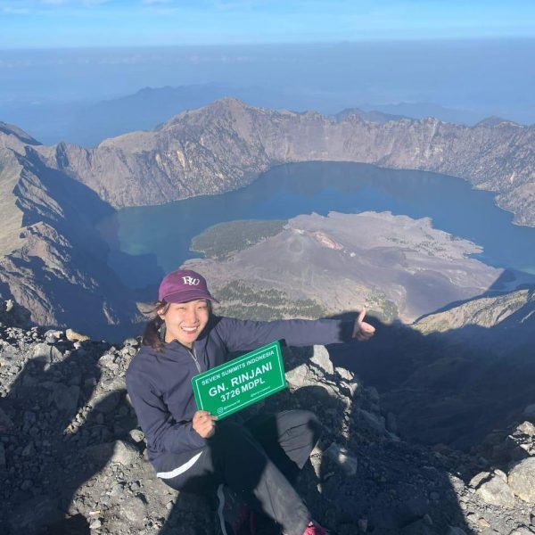 Hiker reaching the summit during Rinjani trekking at Mount Rinjani 3726 mdpl with Segara Anak Lake view in Lombok Indonesia