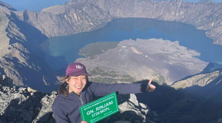 Hiker reaching the summit during Rinjani trekking at Mount Rinjani 3726 mdpl with Segara Anak Lake view in Lombok Indonesia