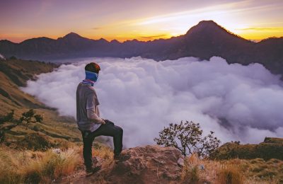 Hiker enjoying sunrise above the clouds during Rinjani trekking adventure on Mount Rinjani Lombok Indonesia